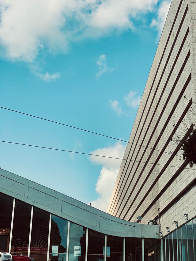 low angle view of a modern concrete building with glass windows under a bright blue sky with thin power lines overhead