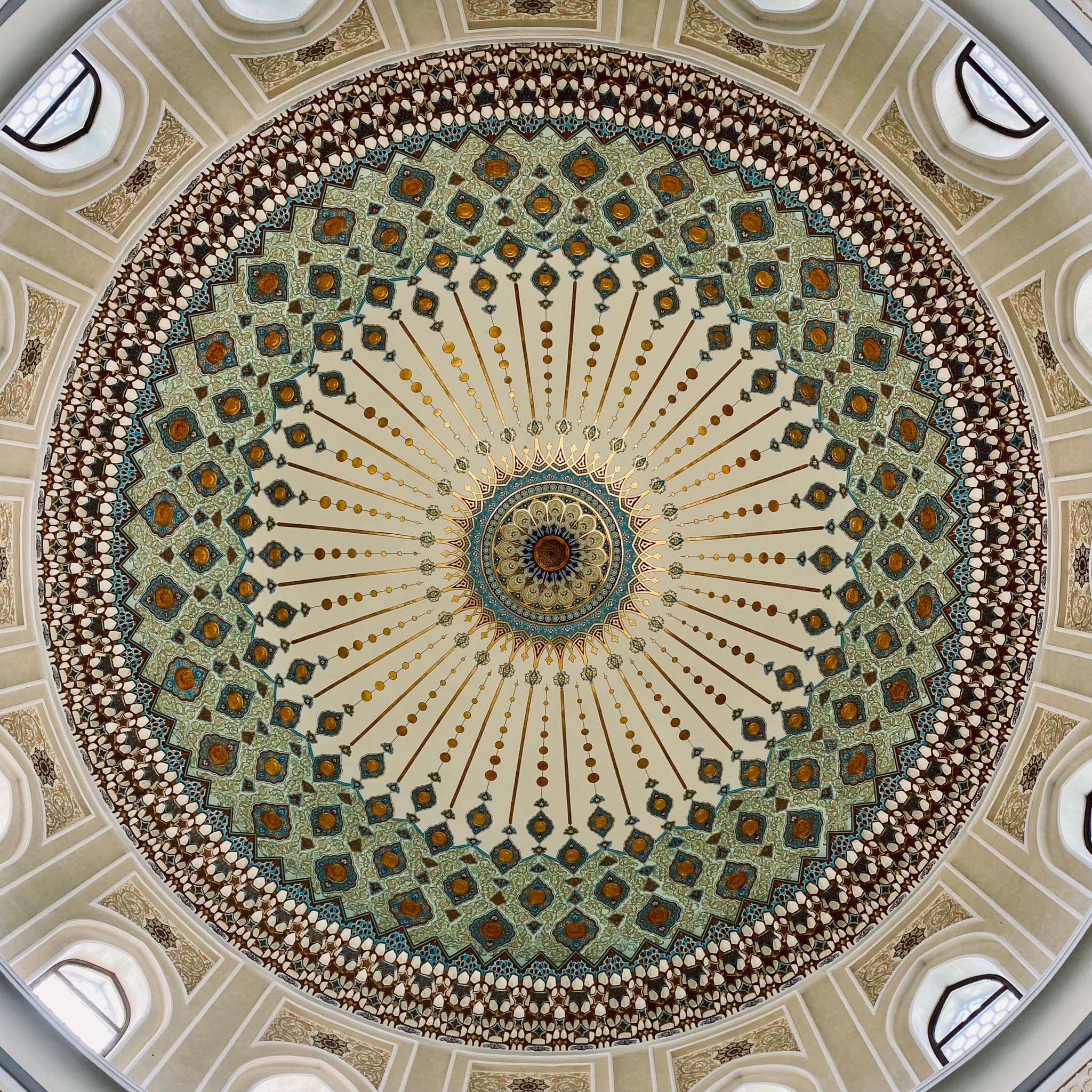 symmetrical view of an ornate mosque dome featuring intricate geometric patterns, soft daylight, and circular architectural details in a quiet interior space