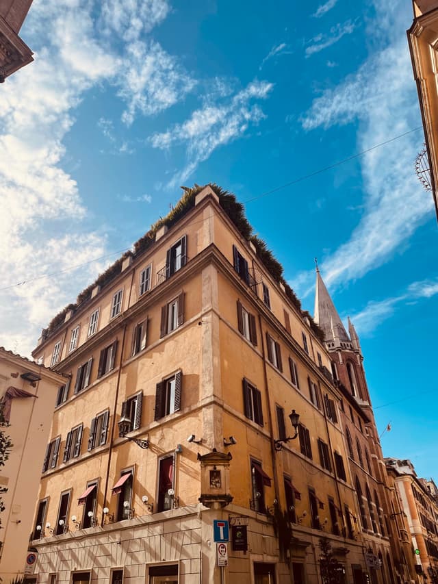 low angle view of a yellow apartment building in rome under a bright blue sky with white clouds during the day