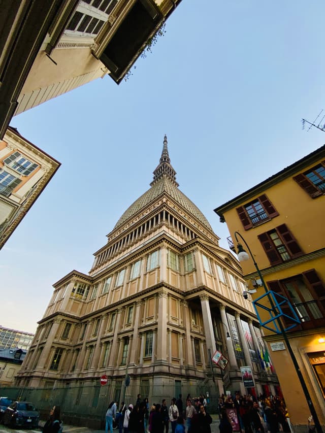 mole antonelliana tower in turin italy viewed from street level under clear blue sky with surrounding historic buildings and pedestrians