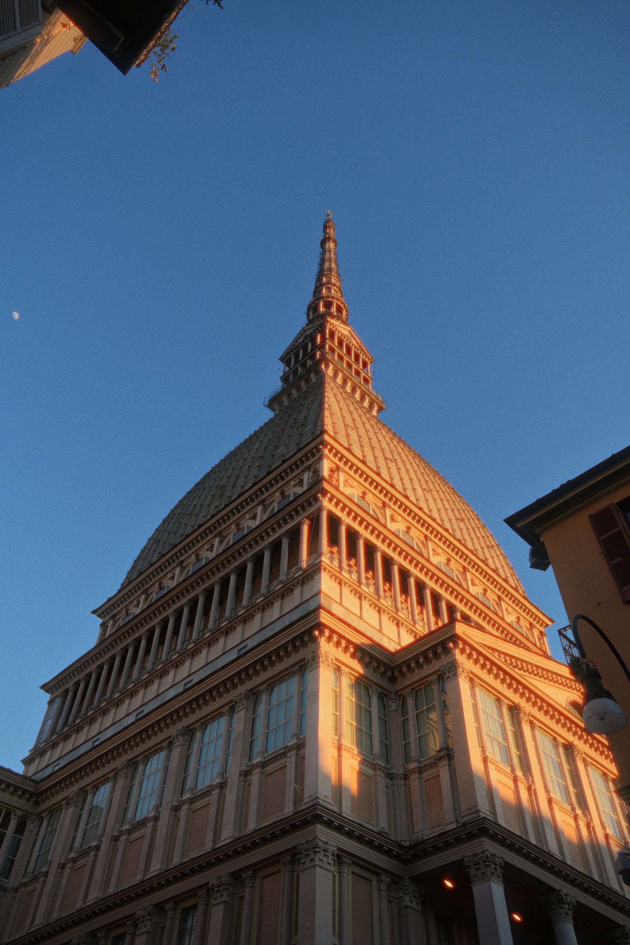 mole antonelliana tower in turin during golden hour with clear blue sky and sharp architectural details captured from a low angle