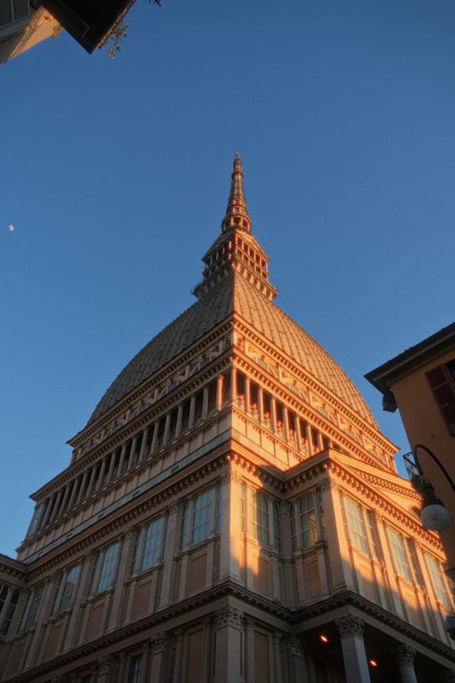 mole antonelliana tower in turin during golden hour with clear blue sky and sharp architectural details captured from a low angle