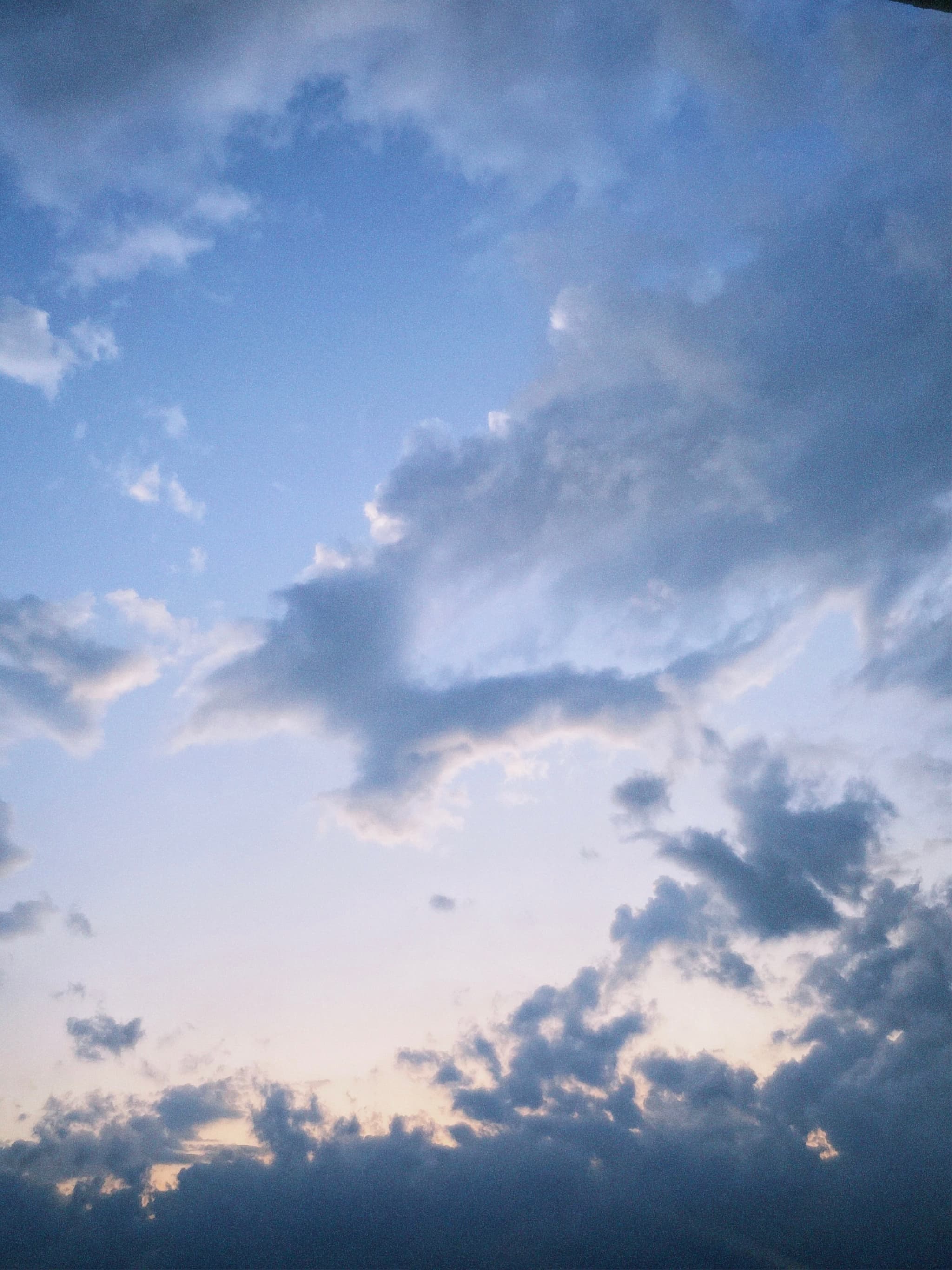 scattered gray clouds drift across a pale blue sky during late afternoon, showing soft light and a quiet, open atmosphere