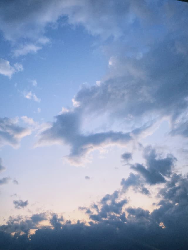 scattered gray clouds drift across a pale blue sky during late afternoon, showing soft light and a quiet, open atmosphere