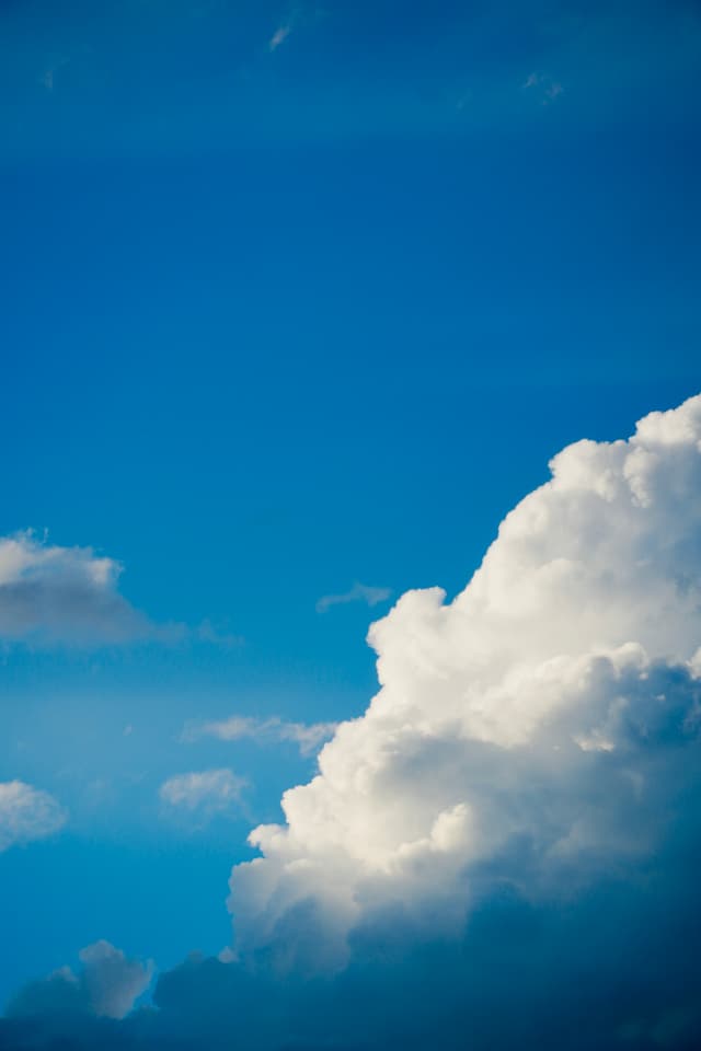 bright white cumulus cloud against a deep blue sky, captured in direct sunlight with high contrast and clear midday weather conditions