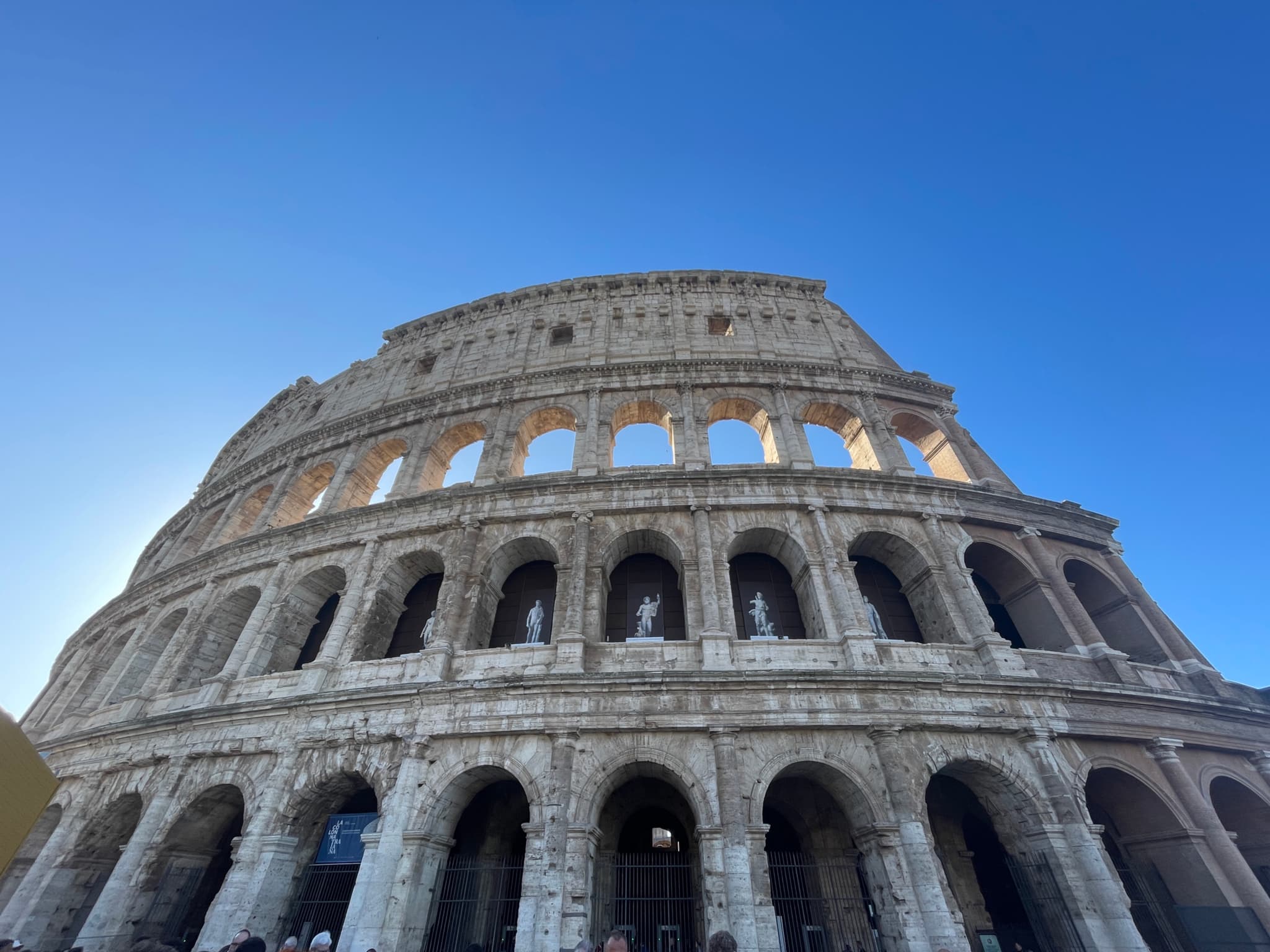 low angle view of the ancient stone colosseum in rome under a clear blue sky during a sunny day in italy