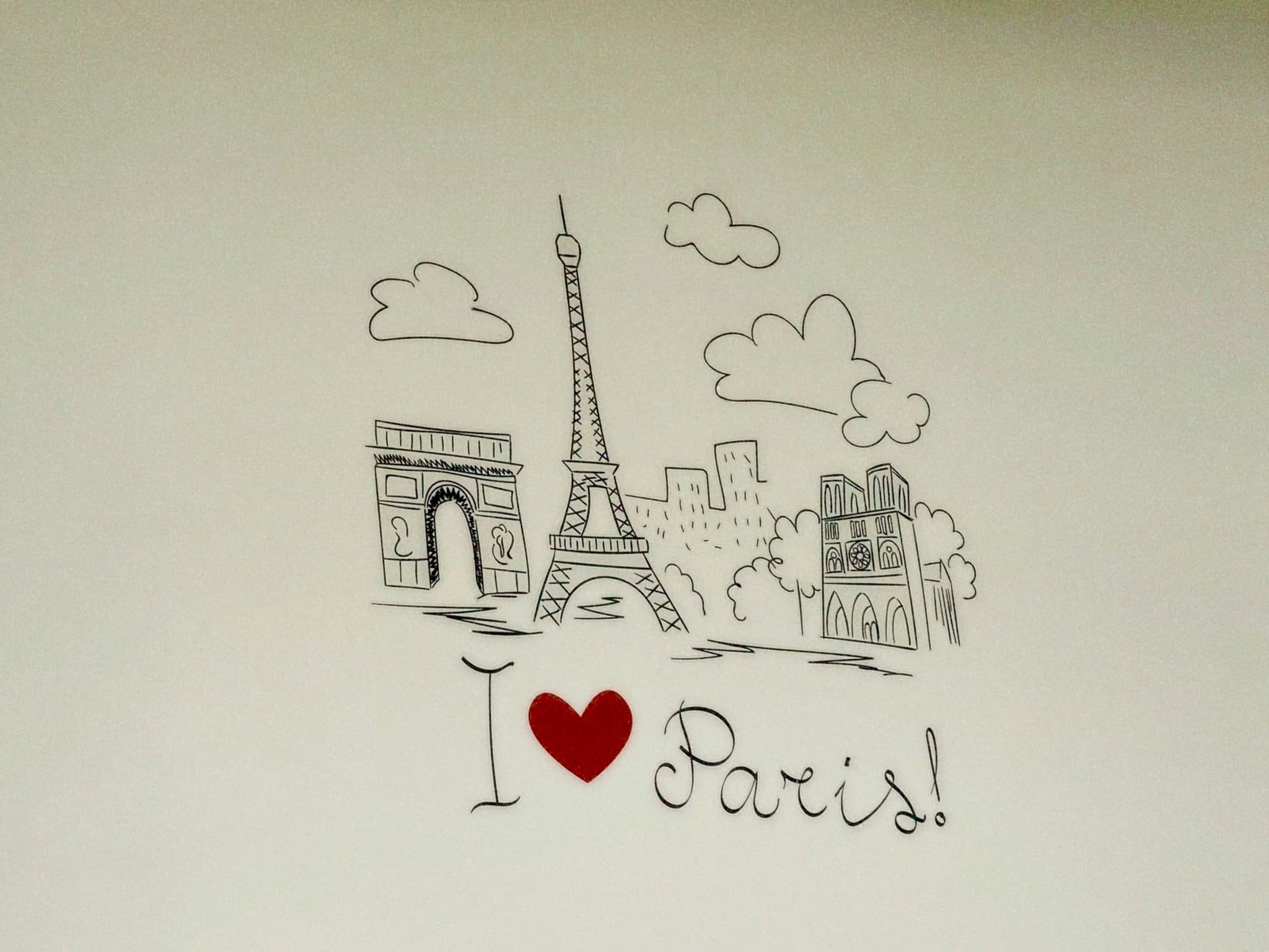 black ink drawing of eiffel tower and paris landmarks on a plain wall with a red heart icon and handwritten text